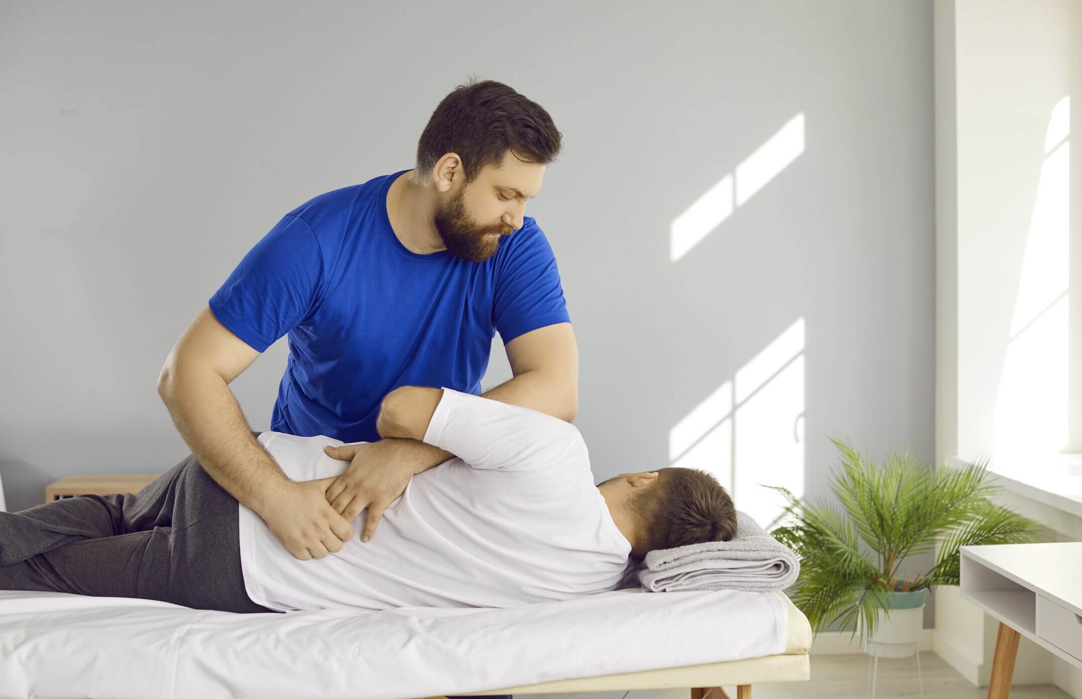 Chiropractor adjusting patient's back on table.